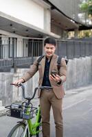 ásia homem de negocios dentro uma terno é equitação uma bicicleta em a cidade ruas para dele manhã comutar para trabalhar. eco transporte conceito, sustentável estilo de vida conceito foto