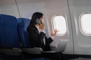 bem sucedido jovem ásia o negócio mulher senta dentro avião cabine avião e trabalhando a partir de em qualquer lugar. vôo às primeiro classe foto