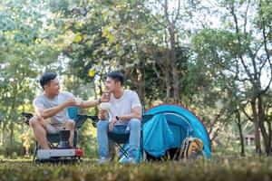 masculino gay casal ásia viajando com barraca acampamento ao ar livre e vários aventura estilo de vida caminhada ativo verão período de férias. bebendo café e falando juntos foto