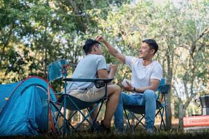 masculino gay casal ásia viajando com barraca acampamento ao ar livre e vários aventura estilo de vida caminhada ativo verão período de férias. bebendo café e falando juntos foto