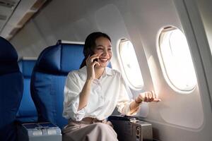 viajando e tecnologia. vôo às primeiro aula. jovem o negócio mulher passageiro usando Smartphone enquanto sentado dentro avião voar foto