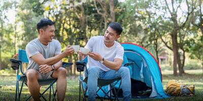 masculino gay casal ásia viajando com barraca acampamento ao ar livre e vários aventura estilo de vida caminhada ativo verão período de férias. bebendo café e falando juntos foto