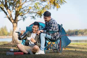 feliz ásia masculino gay casal em acampamento juntos dentro uma floresta. romântico vocação viagem. lgbt conceito foto