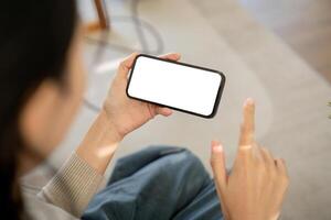 brincar Smartphone do uma mulher segurando e usando Móvel telefone com em branco tela enquanto em a sofá com sentindo-me relaxado foto