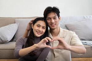 adorável jovem casal ásia é fazer coração placa com mãos às lar. namorados dia celebração foto