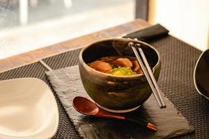 sopa de ramen japonesa com frango, ovo, cebolinha e couve em restaurante foto