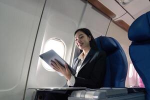 bem sucedido jovem ásia o negócio mulher senta dentro avião cabine avião e trabalhando a partir de em qualquer lugar. vôo às primeiro classe foto