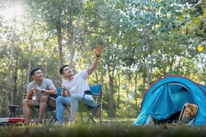 masculino gay casal ásia viajando com barraca acampamento ao ar livre e vários aventura estilo de vida caminhada ativo verão período de férias. bebendo café e falando juntos foto