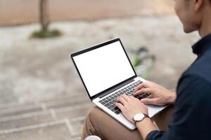 homem de negocios digitando em brincar computador portátil com em branco branco tela às urbano lado de fora foto