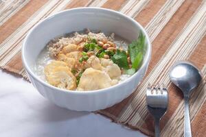 Bubur ayam Sucabumi contém branco arroz mingau com lado pratos do frito frango fatias foto