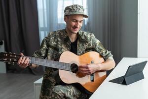 alegre sorridente jovem militares homem vestindo cáqui uniforme segurando guitarra. foto