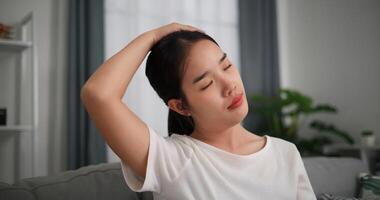 seletivo foco, feliz jovem mulher é praticando ioga e alongamento dela pescoço às casa com olhos fechado, relaxante corpo e mente sozinho em sofá dentro a vivo quarto, relaxamento estilo de vida foto