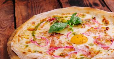 Itália pizza com ovo gema, presunto e cebola foto