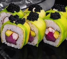 Sushi lista coberto com abacate com atum e Preto caviar foto