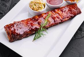 grelhado carne de porco costelas dentro churrasco molho e querida com Chucrute em branco prato foto