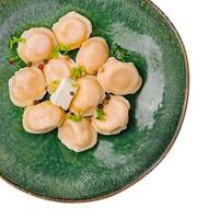 pelmeni com manteiga e verduras em verde prato foto