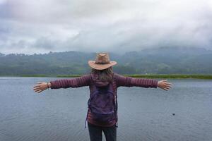 viajante mulher abre dela braços dentro frente do uma lagoa Como uma placa do relaxamento dentro Peru. foto