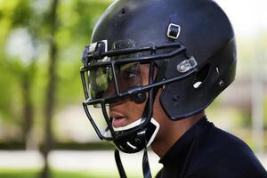 perfil jovem Preto homem dentro futebol capacete foto