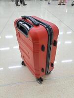 uma vermelho mala de viagem com Preto linhas em a zíper e rodas é muito adequado para grandes viagens ou viagem foto