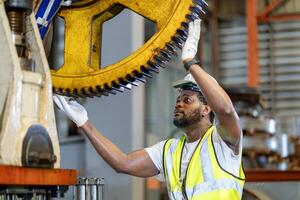 africano americano mecânico trabalhador é verificação a engrenagem para hidráulico máquina dentro metal aço fabricação fábrica para manutenção e inspeção foto