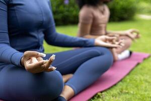 africano americano mulher e dela filha dentro ioga terno estão relaxantemente praticando meditação exercício dentro a parque para atingir felicidade a partir de interior Paz sabedoria para saudável mente e alma foto