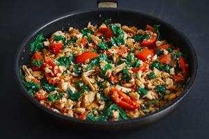 Uma deliciosa mistura de vegetais fritos com tofu, baixo teor de gordura, vegetariana, sobre um fundo preto foto