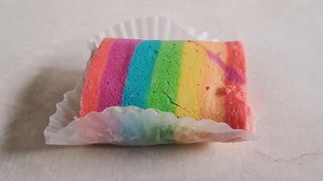 uma peça do bolo dentro arco Iris cores foto
