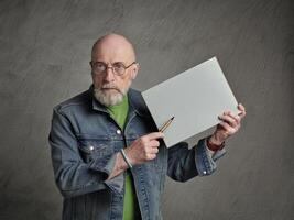 Senior homem é segurando uma em branco Folha do papel e uma caneta, apresentação conceito foto