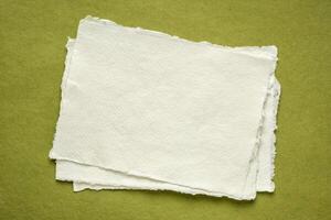 pequeno Folha do em branco branco khadi papel contra verde trapo papel foto