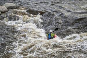 caiaque surfar a onda dentro água Branca parque em a poudre rio dentro centro da cidade do forte collins, Colorado foto