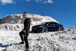 bonito jovem modelo posando com carro. à moda atraente cara dentro oculos escuros. foto