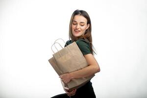 lindo moça segurando mercearia compras bolsa. branco fundo. jovem menina com saco debaixo braço. luz Castanho compras bolsa. fechar-se. foto