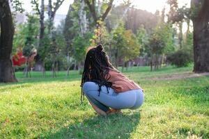 jovem europeu mulher é sentado em uma Relva e fazendo ioga exercício. saudável estilo de vida ao ar livre. foto