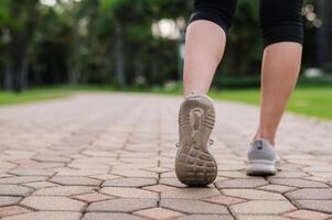 corredor mulher. fechar acima pessoa Treinamento esporte corredor jovem fêmea sapato em andar caminho dentro público parque. ginástica perna e pé exercício atleta. maratona dentro natureza. ativo saudável estilo de vida exercite-se conceito. foto