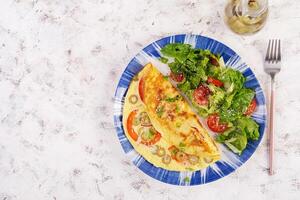 omelete com tomates, verde azeitonas e fresco salada em azul placa. fritada - italiano omelete. topo visualizar, plano deitar foto