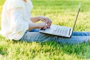 pequeno menina sentado dentro a parque e trabalhando com computador portátil. Educação, estilo de vida, tecnologia conceito foto