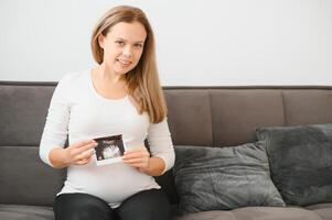 grávida mulheres segurando eco As fotos dentro mão