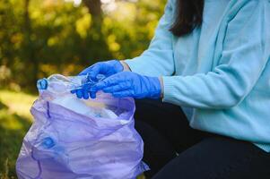 mão coloca plástico detritos dentro a lixo saco dentro a parque foto