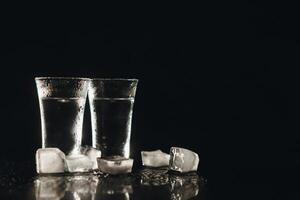 vodka tiros com gelo em Preto mesa, cópia de espaço. foto