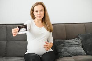 grávida mulheres segurando eco As fotos dentro mão