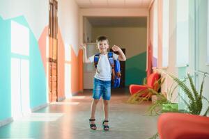 retrato do uma estudante em pé com uma mochila em a esvaziar escola corredor. costas para escola. foto