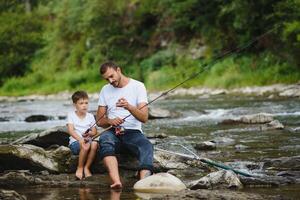 uma pai ensino dele filho quão para peixe em uma rio lado de fora dentro verão brilho do sol foto