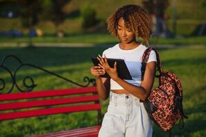 conectados comunicação, Educação ou trabalhos conceito. bonita africano americano senhora com tábua computador às parque foto