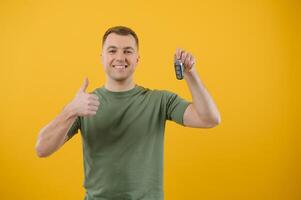 chocado jovem homem posando isolado em amarelo laranja fundo, estúdio retrato. pessoas emoções estilo de vida conceito. zombar acima cópia de espaço. segurando dentro mão carro chaves, mostrando polegar acima foto