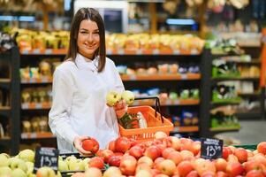 mulher dentro uma supermercado às a vegetal estante compras para mantimentos, ela é escolhendo foto