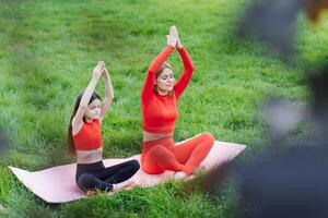 mãe e filha fazendo ioga exercícios em Relva dentro a parque às a dia Tempo foto
