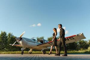 retrato do dois sorridente o negócio pessoas, homem e mulher, caminhando de avião hangar dentro aeroporto campo foto