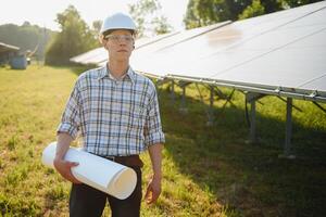 Planta de energia solar. homem de pé perto de painéis solares. energia renovável. foto