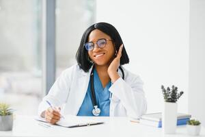 retrato do africano americano mulher médico sorridente dentro hospital. foto