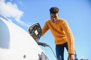 africano americano homem cobrando dele elétrico carro. foto